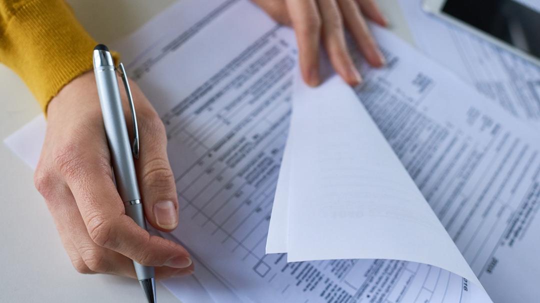 Woman filling out paperwork about self employment health insurance tax deductions.